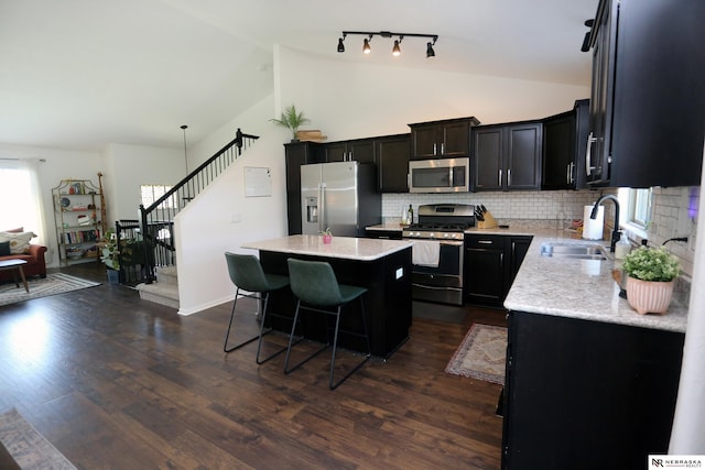 13719 S 43rd Ave, Bellevue, NE 68123 - kitchen with appliances with stainless steel finishes, a kitchen island, a kitchen bar, tasteful backsplash, and dark wood finished floors