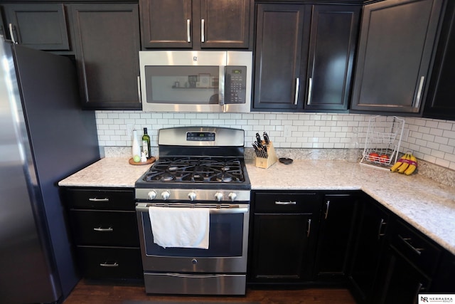 13719 S 43rd Ave, Bellevue, NE 68123 - kitchen featuring appliances with stainless steel finishes, tasteful backsplash, dark wood-style flooring, and light stone countertops
