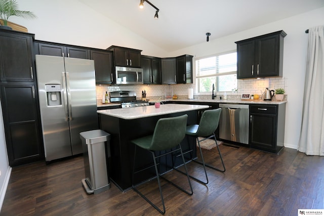 13719 S 43rd Ave, Bellevue, NE 68123 - kitchen with appliances with stainless steel finishes, vaulted ceiling, a kitchen island, tasteful backsplash, and dark wood-style floors