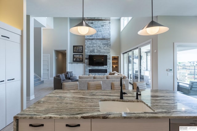 6217 N 295th St, Valley, NE 68064 - kitchen featuring light stone counters, a fireplace, hanging light fixtures, a high ceiling, and white cabinetry