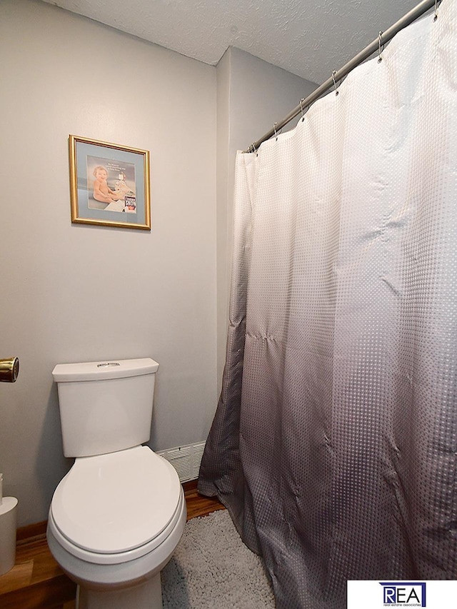 4711 S 102nd St, Omaha, NE 68127 - bathroom featuring wood finished floors, a shower with shower curtain, and a textured ceiling