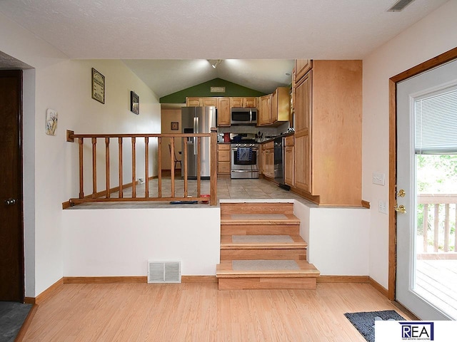 4711 S 102nd St, Omaha, NE 68127 - kitchen featuring appliances with stainless steel finishes, light wood finished floors, vaulted ceiling, and brown cabinetry