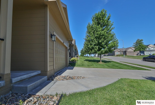 17457 Ames Ave, Omaha, NE 68116 - view of grassy yard with a garage, a residential view, and driveway