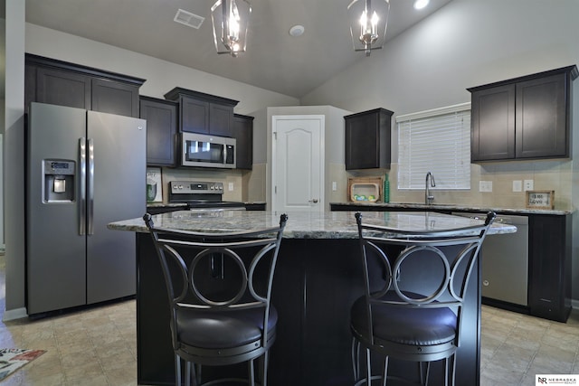 17457 Ames Ave, Omaha, NE 68116 - kitchen featuring appliances with stainless steel finishes, a center island, light stone counters, a kitchen breakfast bar, and lofted ceiling