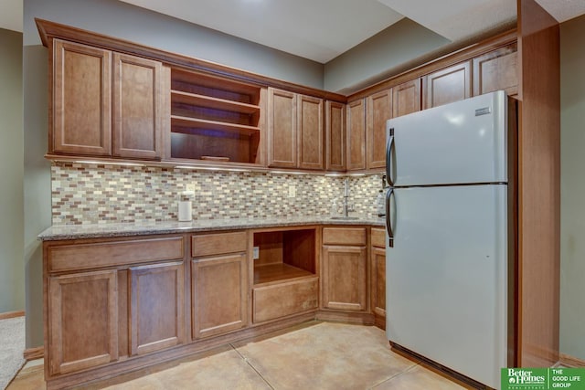 19311 Josephine St, Gretna, NE 68028 - kitchen featuring freestanding refrigerator, open shelves, light stone counters, and backsplash