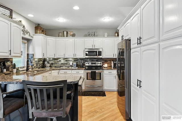 8127 S 105th St, La Vista, NE 68128 - kitchen featuring appliances with stainless steel finishes, a kitchen bar, a peninsula, white cabinets, and recessed lighting