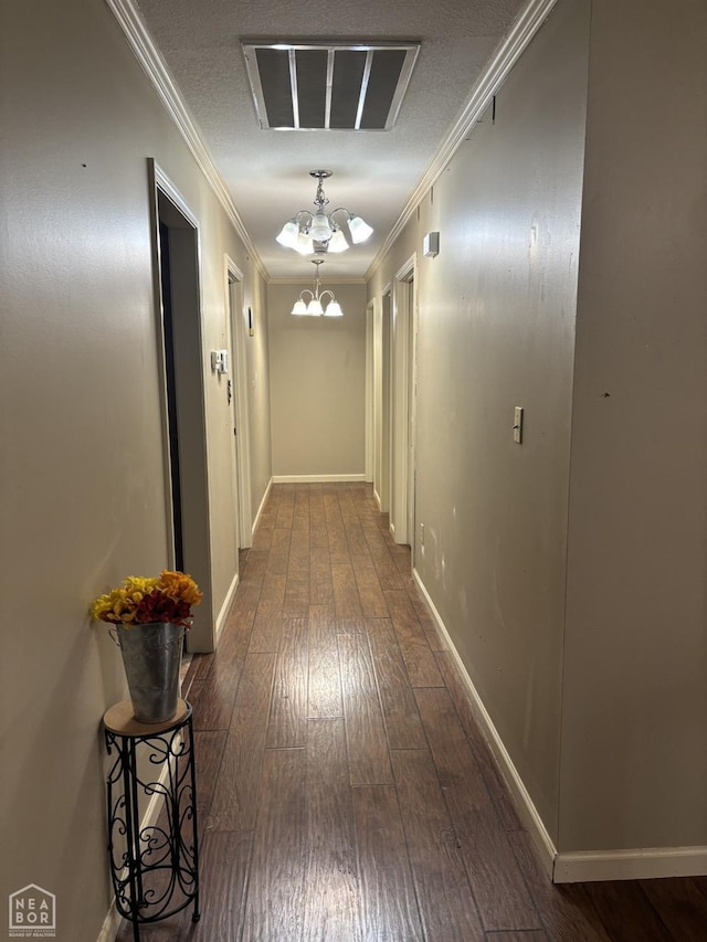 hall with ornamental molding, visible vents, wood-type flooring, and an inviting chandelier