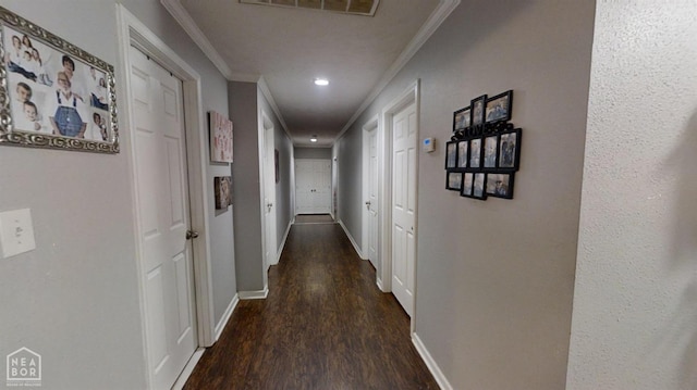 corridor with visible vents, baseboards, crown molding, and wood finished floors