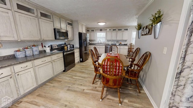 kitchen featuring a sink, glass insert cabinets, a textured ceiling, and stainless steel appliances