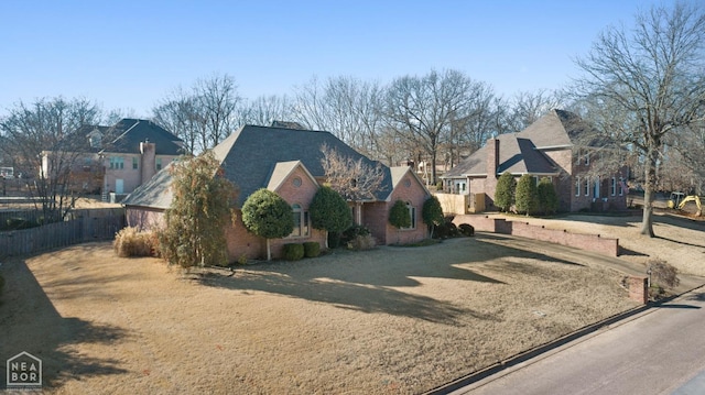 view of front of home with a residential view, brick siding, and fence