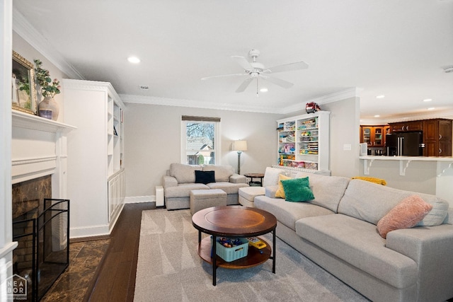 living room featuring ornamental molding, recessed lighting, dark wood finished floors, a fireplace with raised hearth, and ceiling fan