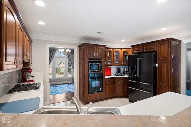 kitchen with glass insert cabinets, a sink, black appliances, and crown molding