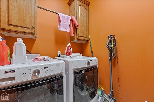 clothes washing area featuring cabinet space and washer and clothes dryer