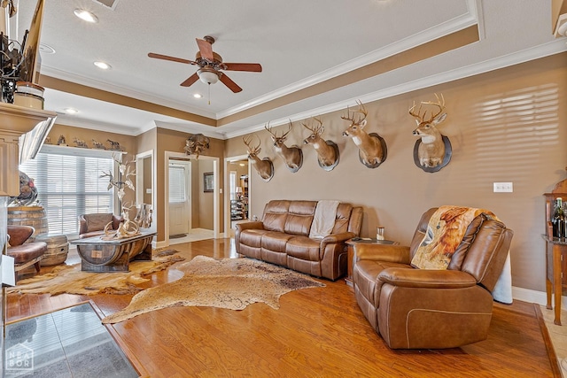 living room with baseboards, recessed lighting, a ceiling fan, crown molding, and a tray ceiling
