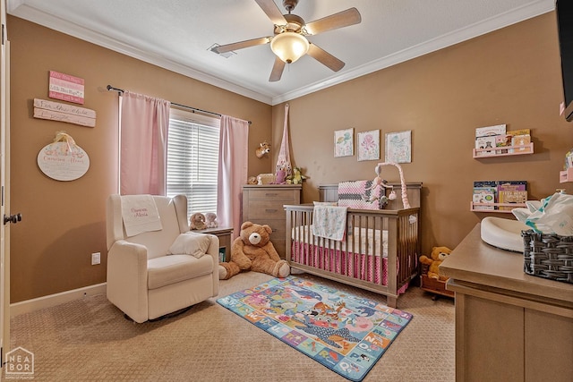 carpeted bedroom with ceiling fan, baseboards, ornamental molding, and a crib