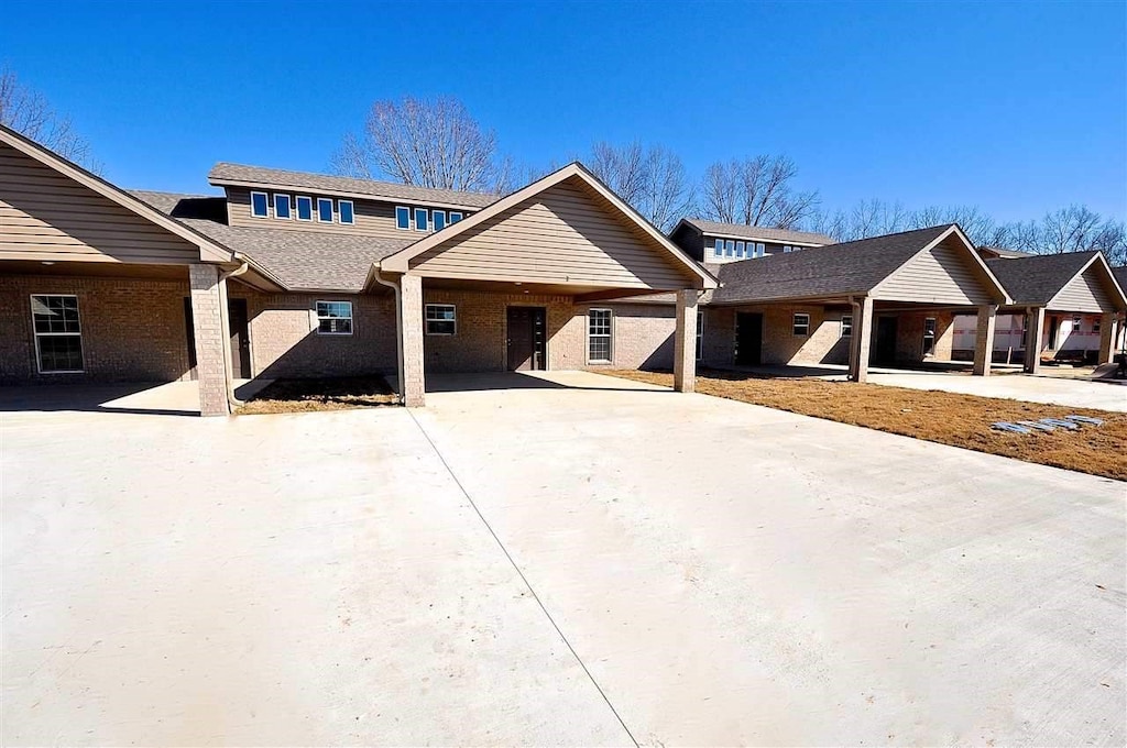view of front of home featuring an attached carport, brick siding, and driveway