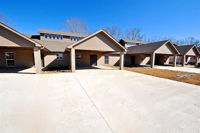 view of front of home featuring an attached carport, brick siding, and driveway