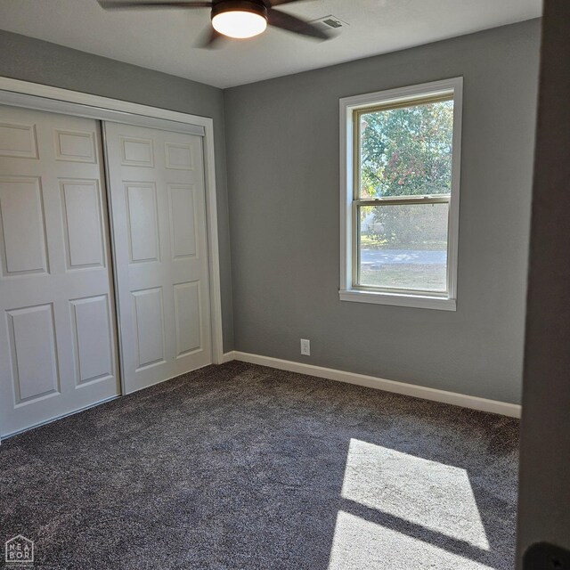 unfurnished bedroom featuring dark carpet, baseboards, a closet, and ceiling fan