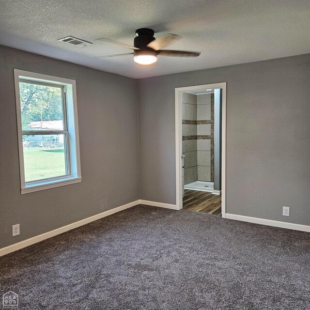 carpeted empty room with visible vents, baseboards, a textured ceiling, and ceiling fan