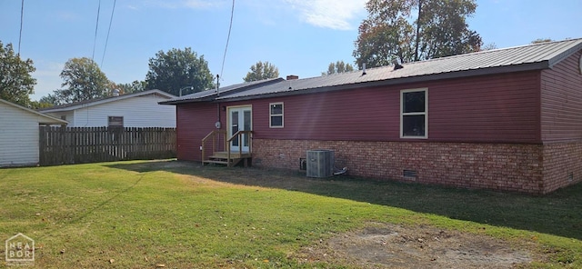 back of property with entry steps, a yard, metal roof, fence, and cooling unit