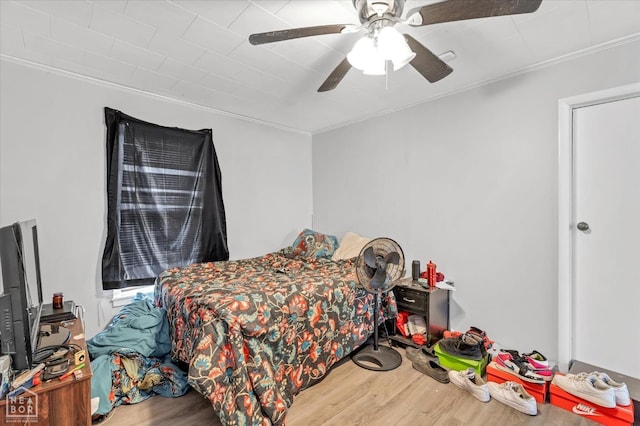 bedroom featuring a ceiling fan, crown molding, and wood finished floors