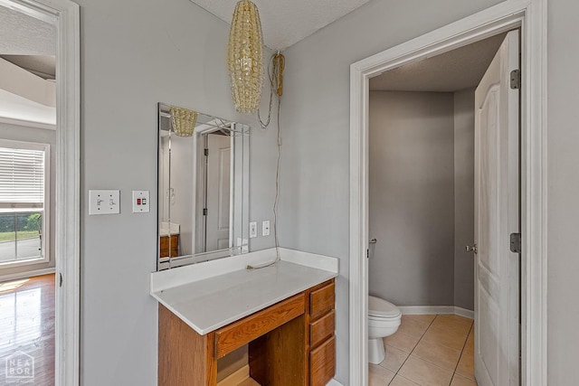 bathroom featuring a textured ceiling, vanity, tile patterned flooring, toilet, and baseboards