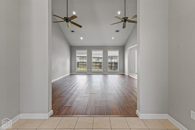 unfurnished living room featuring high vaulted ceiling, tile patterned flooring, baseboards, and a ceiling fan