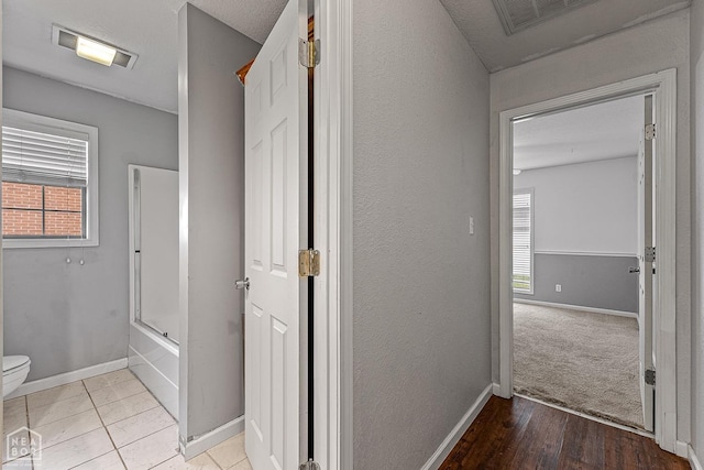 corridor with visible vents, baseboards, and wood finished floors
