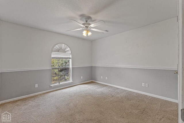 empty room featuring a textured ceiling, baseboards, a ceiling fan, and carpet