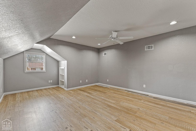 interior space with visible vents, baseboards, a ceiling fan, a textured ceiling, and wood-type flooring