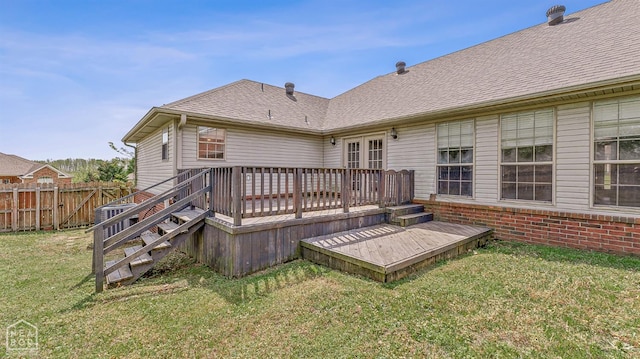 rear view of house with french doors, a wooden deck, a yard, fence, and a shingled roof