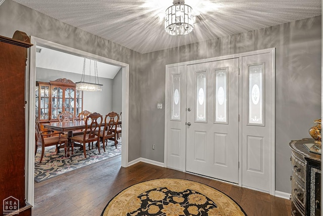 foyer entrance featuring wood-type flooring, baseboards, and an inviting chandelier
