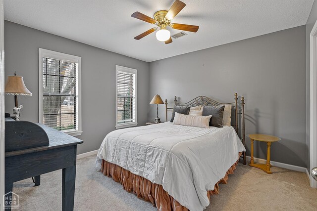 bedroom with baseboards, a textured ceiling, visible vents, ceiling fan, and light colored carpet