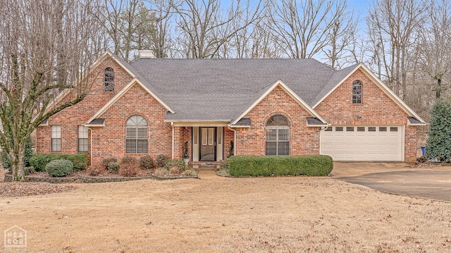 traditional home with a garage, brick siding, a chimney, a shingled roof, and concrete driveway