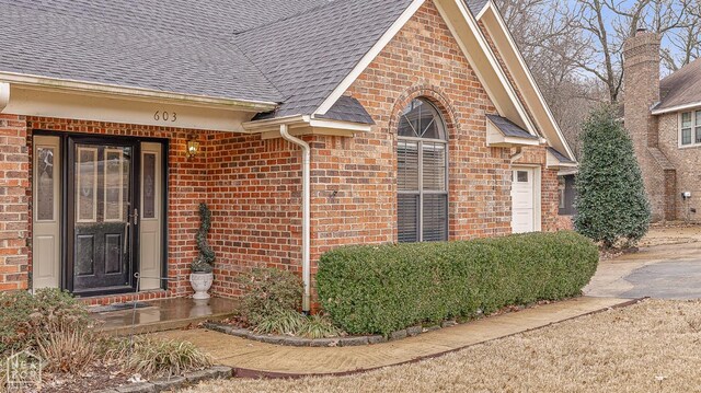 property entrance with brick siding and roof with shingles