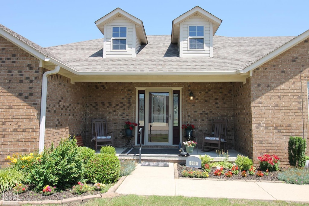 5005 S 28th St, Paragould, AR 72450 - entrance to property featuring a porch, brick siding, and a shingled roof