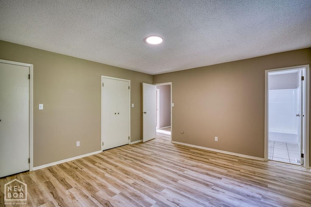 1610 Smoot Dr, Jonesboro, AR 72401 - unfurnished bedroom featuring light wood finished floors, a textured ceiling, and connected bathroom
