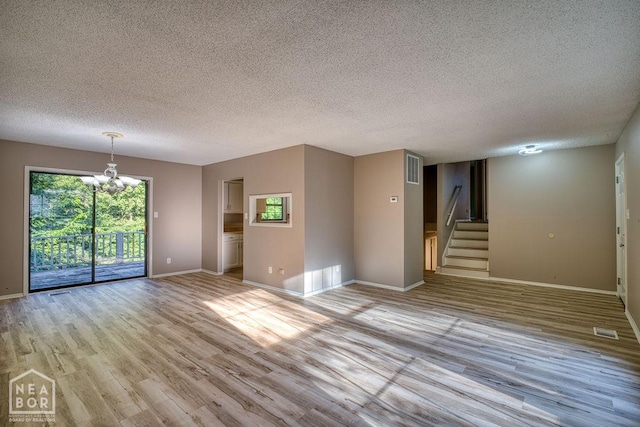 1610 Smoot Dr, Jonesboro, AR 72401 - empty room with a chandelier, stairway, light wood-style floors, and a textured ceiling