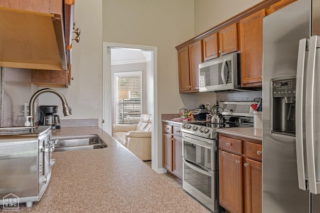 kitchen featuring a sink, appliances with stainless steel finishes, light countertops, and brown cabinets