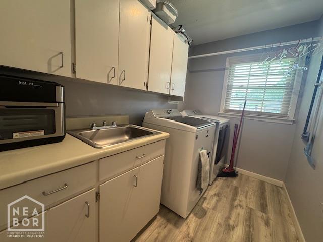 700 11th St, Corning, AR 72422 - laundry area with light wood-style floors, washing machine and dryer, and cabinet space