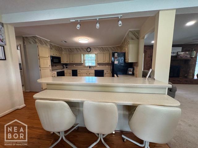 700 11th St, Corning, AR 72422 - kitchen with black appliances, a peninsula, light countertops, and a breakfast bar