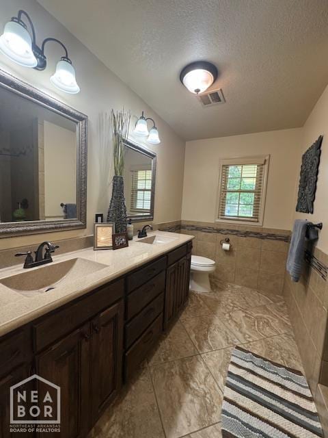 700 11th St, Corning, AR 72422 - bathroom with tile walls, double vanity, a textured ceiling, a wainscoted wall, and tile patterned flooring