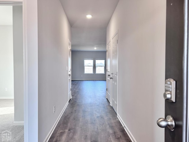 hallway featuring dark wood-style flooring and baseboards