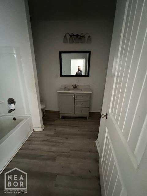 bathroom featuring toilet, wood finished floors, vanity, and bathtub / shower combination