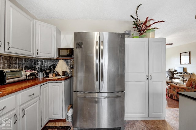154 Mockingbird Cir, Marmaduke, AR 72443 - kitchen with freestanding refrigerator, a textured ceiling, white cabinets, decorative backsplash, and a toaster