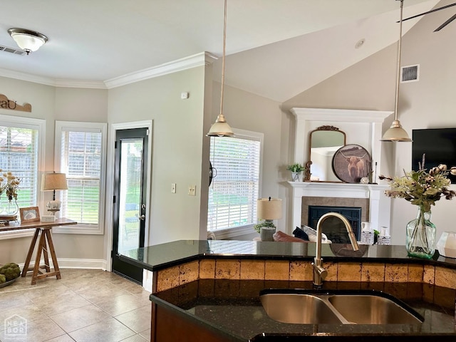 kitchen with visible vents, ornamental molding, a sink, and a tile fireplace