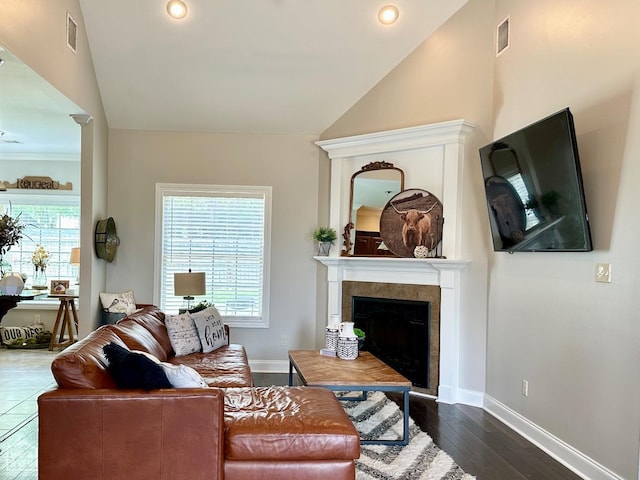 living area with baseboards, visible vents, a tiled fireplace, and lofted ceiling