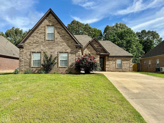 traditional-style home featuring a shingled roof, central AC, a front lawn, and brick siding