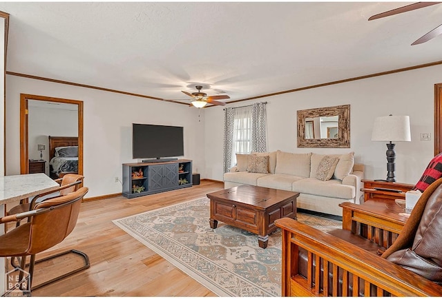 living room with baseboards, a ceiling fan, crown molding, and light wood finished floors