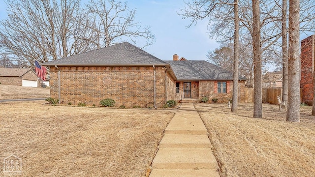 ranch-style home with fence, a shingled roof, a chimney, and brick siding